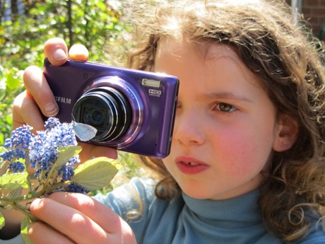 Kid takes a close picture of a butterfly on a flower